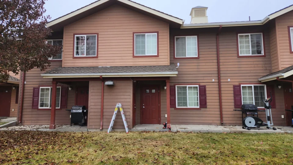 A light red two-story multi-unit housing with a grass front lawn