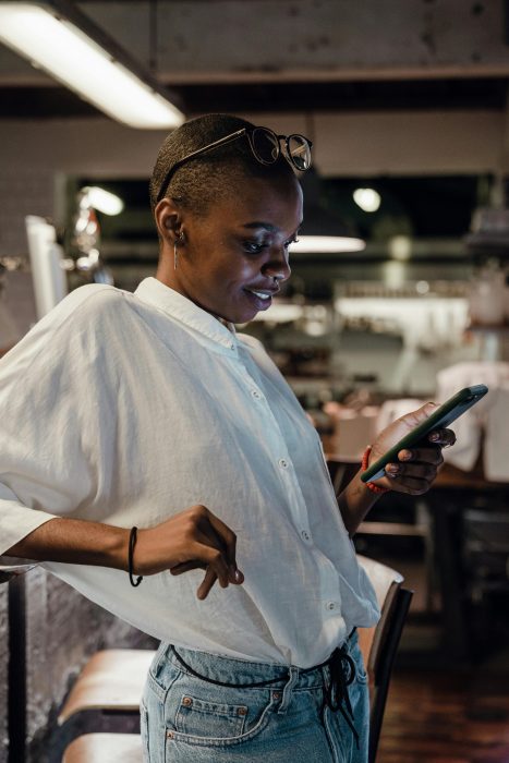 A person in a white shirt holding a phone and looking at it