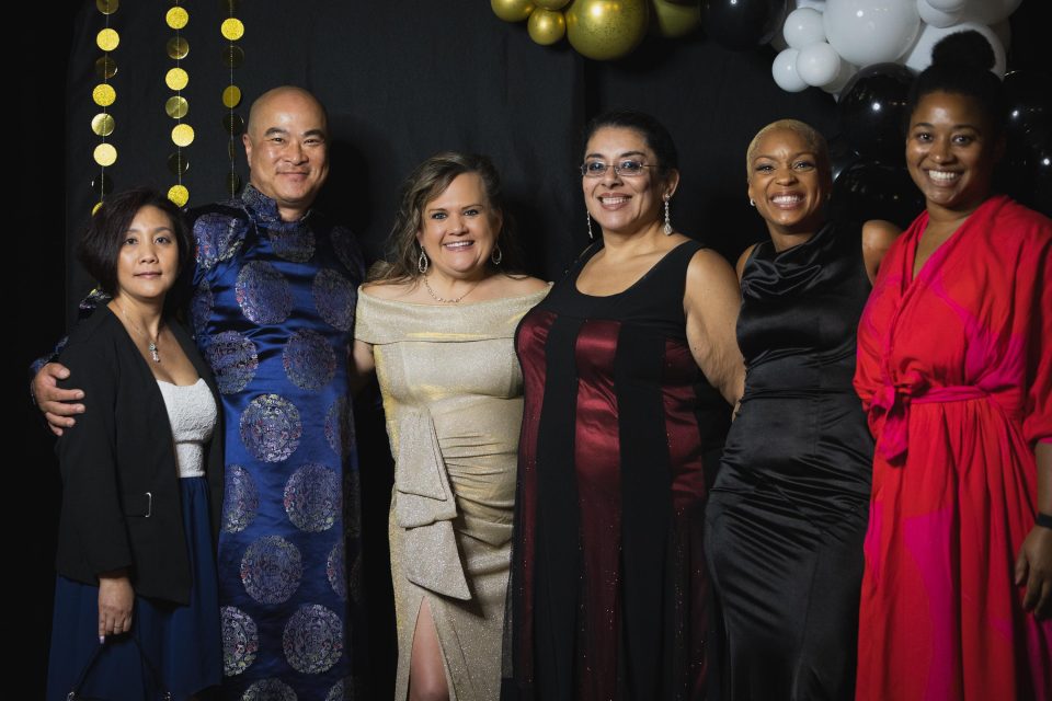 Racially diverse group of people in fancy clothes standing and smiling at the camera