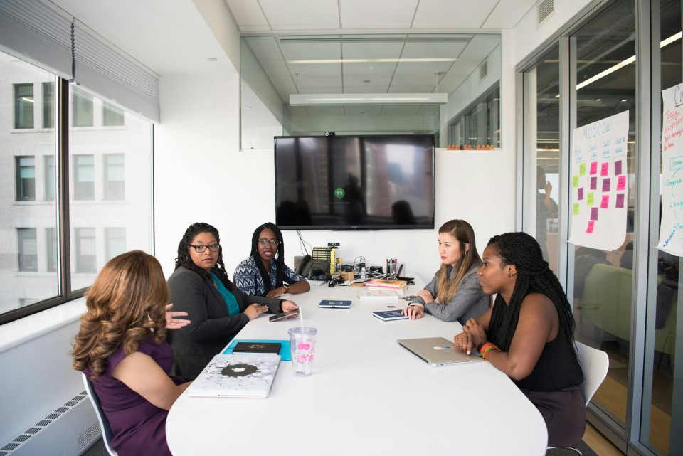 Group of Women gathered inside a sitting at a table in a conference room